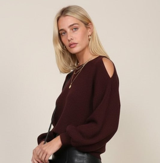 Woman wearing a burgundy sweater with cut-out shoulders and a black leather skirt on a beige background