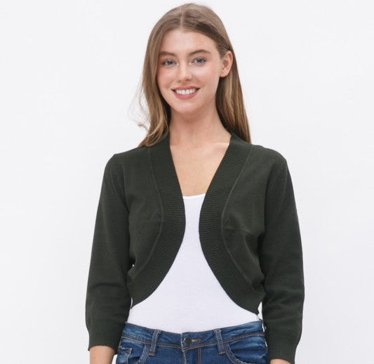 Woman wearing a black cardigan over a white top and blue jeans on a white background