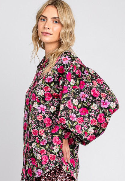 Woman wearing a floral kimono-style top with a sequin skirt on a plain background