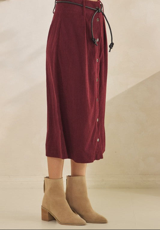 Maroon skirt with buttons and tan boots on a neutral background