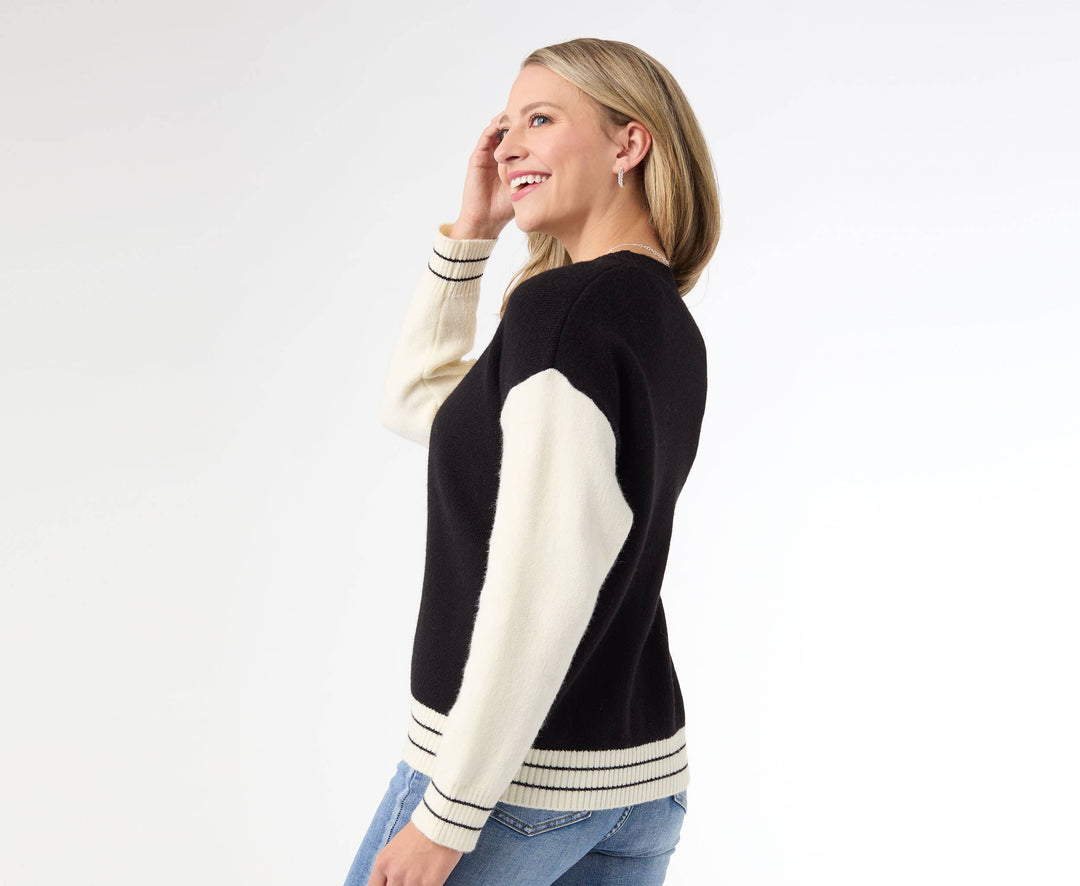 Woman wearing a black and white sweater with blue jeans on a white background