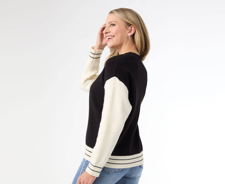 Woman wearing a black and white sweater with blue jeans on a white background