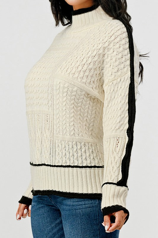 Cream-colored sweater with black accents worn by a person on a white background
