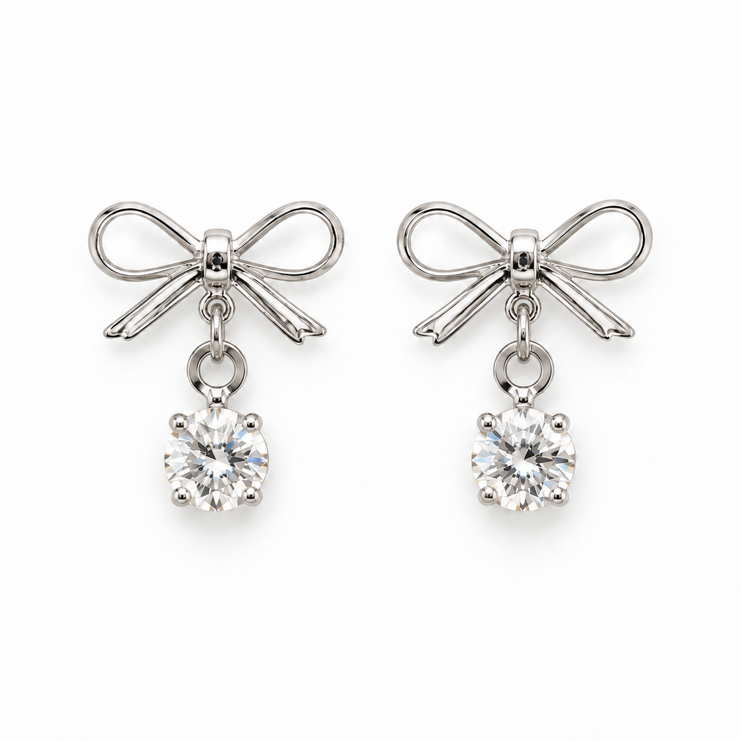 A pair of silver bow stud earrings with clear round-cut gemstones hanging below, shown on a plain white background.