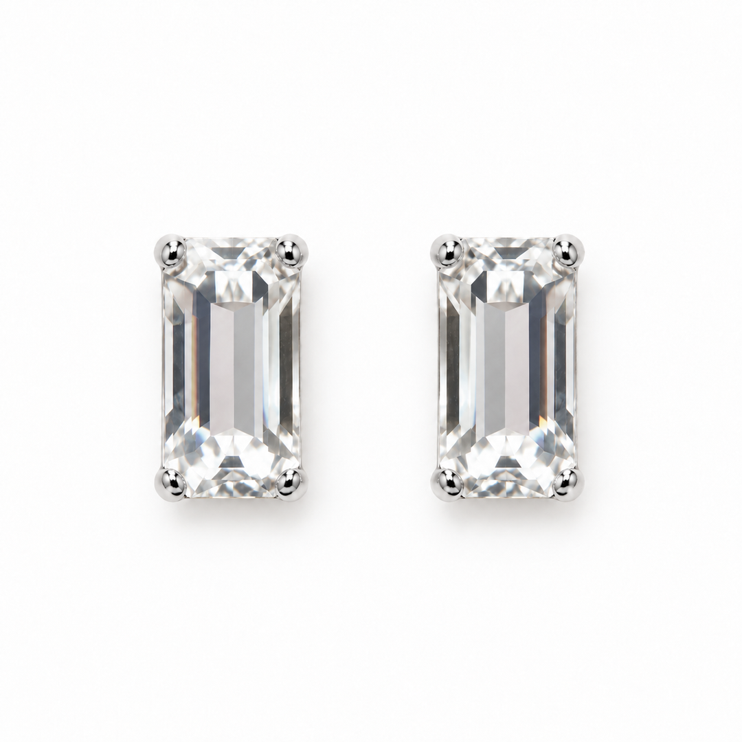A pair of rectangular emerald-cut clear gemstone stud earrings set in silver-toned metal prongs, shown on a plain white background.