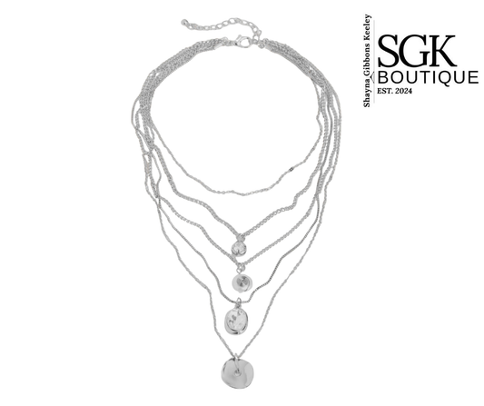 Silver necklace with layered design on a white background, featuring SGK Boutique logo.