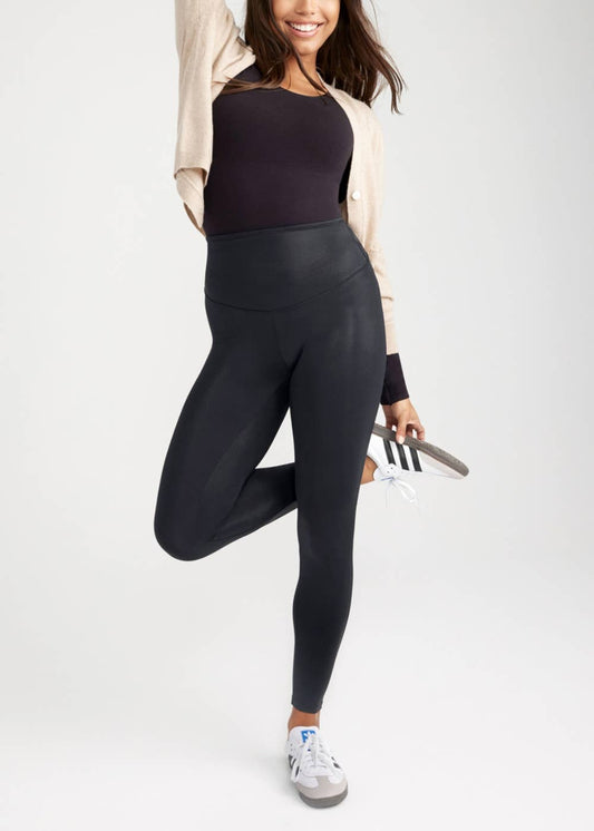 Person wearing black leggings and a dark top on a white background