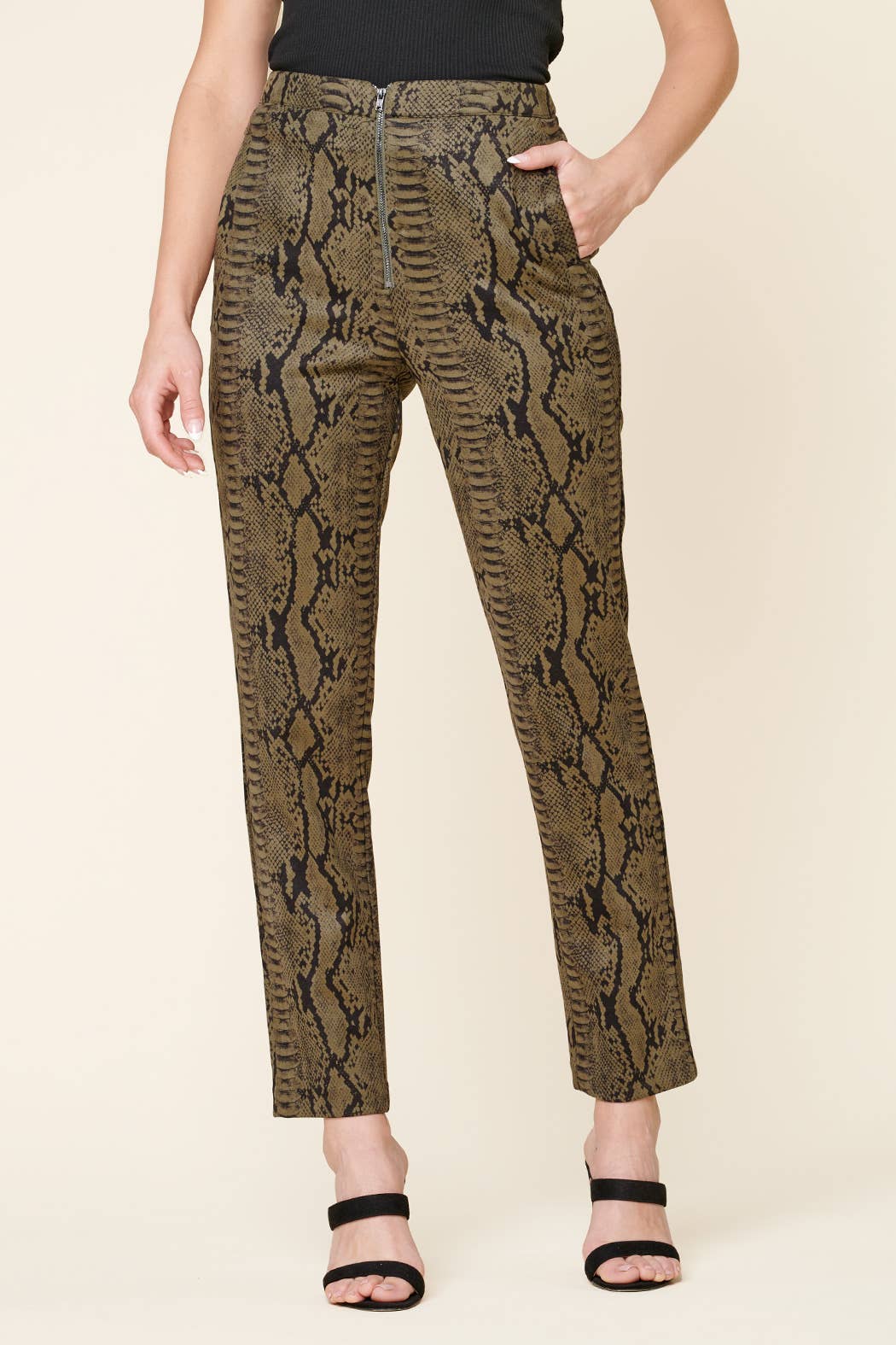 Snakeskin-patterned pants worn by a person on a beige background