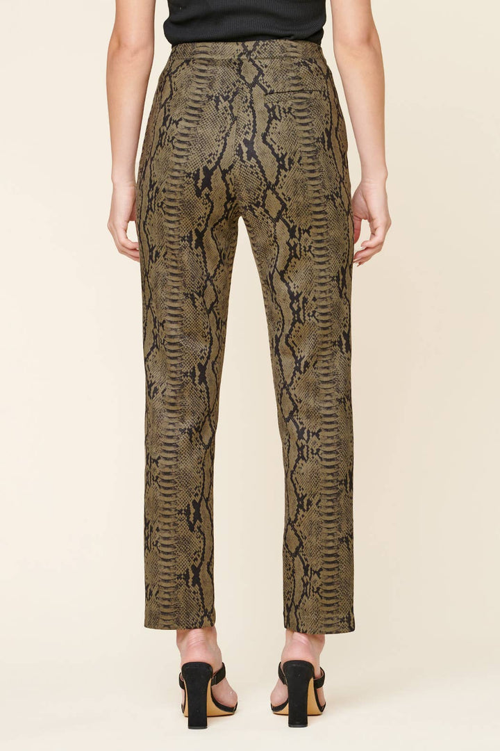 Snakeskin patterned pants worn by a person on a beige background