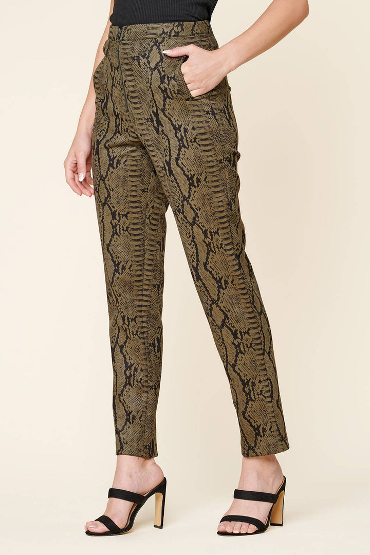 Snakeskin patterned pants worn by a person on a beige background