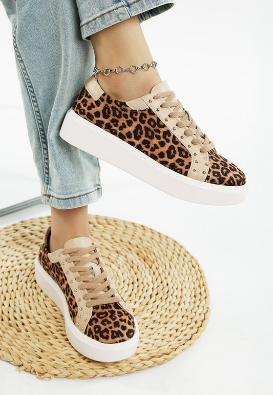 Leopard print sneakers worn with light blue jeans on a woven mat.