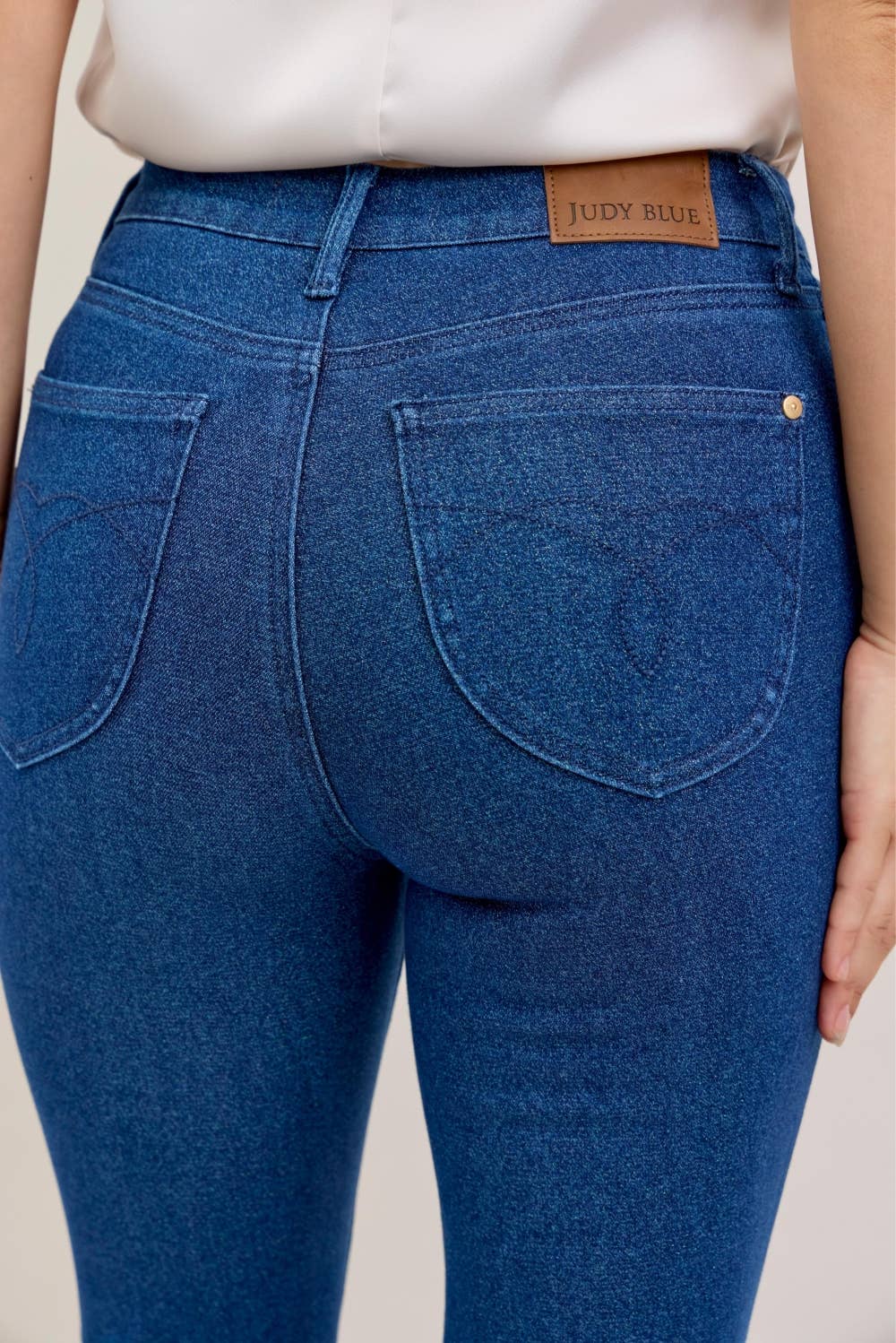 Blue jeans with a Judy Blue label on a neutral background