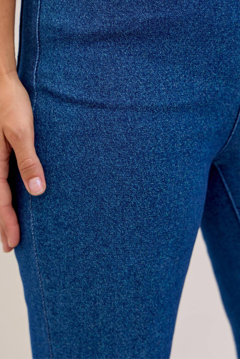 Close-up of blue denim fabric with a hand touching it