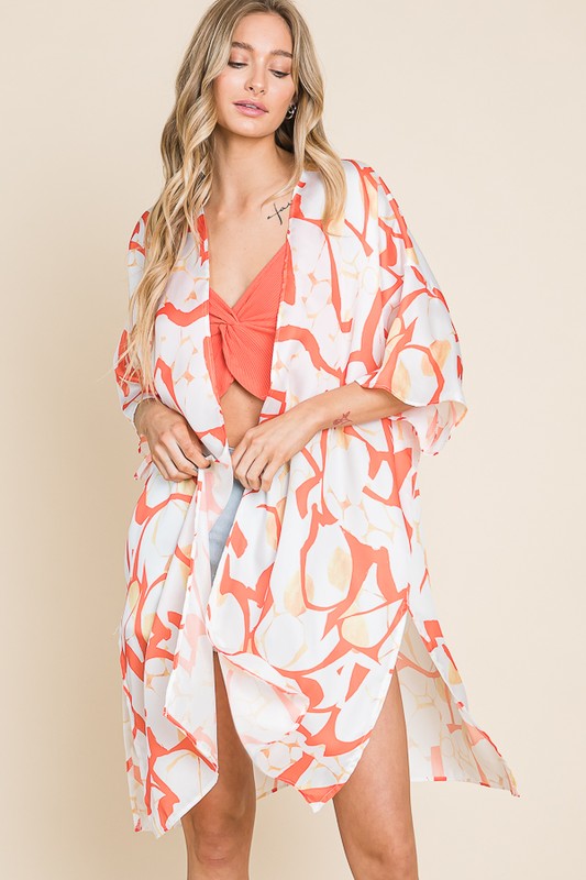Woman wearing a colorful kimono-style cover-up against a beige background