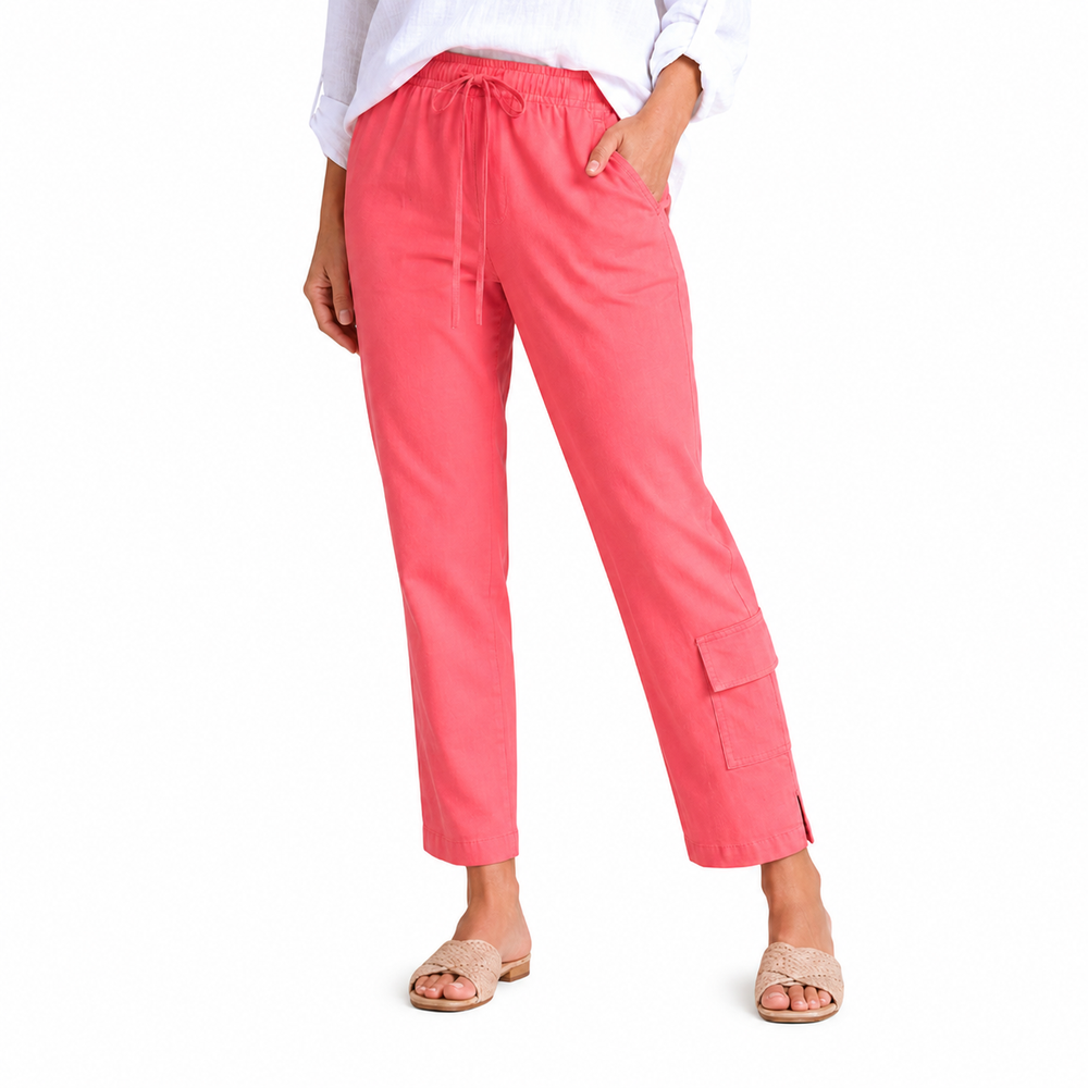 A model wearing bright coral pink cropped pants with a drawstring waist and side cargo pocket, paired with a white top and beige slide sandals, on a solid white background.
