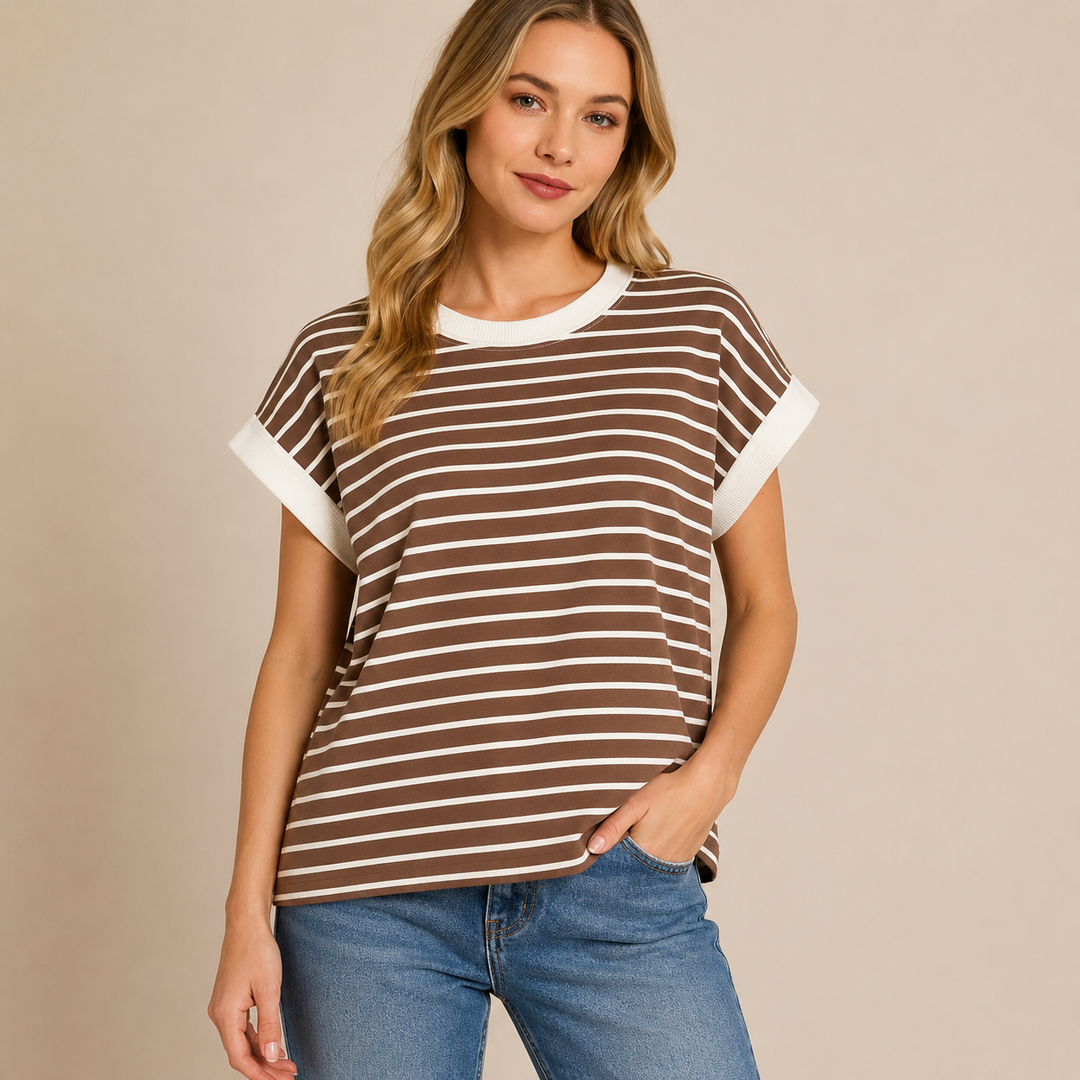 Woman wearing a brown and white striped shirt with blue jeans on a beige background