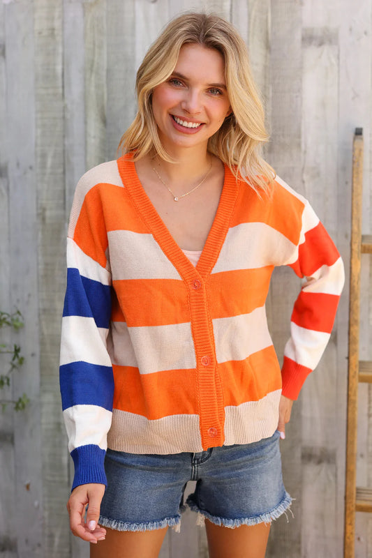 Woman wearing a colorful striped cardigan against a wooden fence background