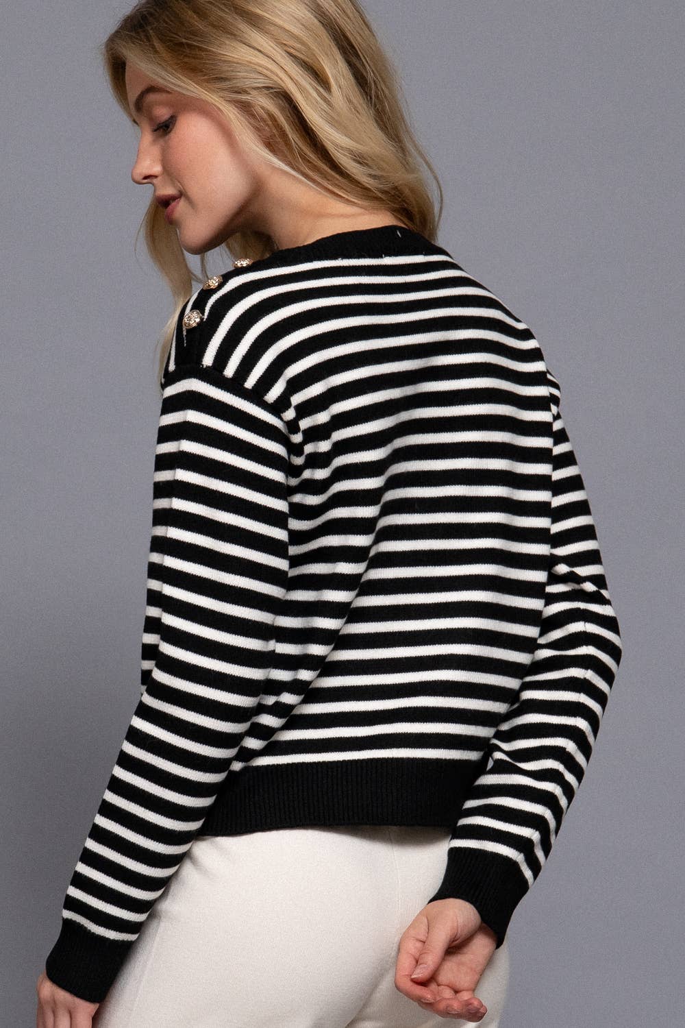 Person wearing a black and white striped sweater against a gray background