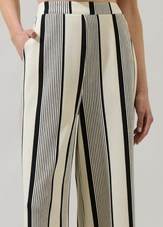 Black and white striped pants worn by a person on a plain background