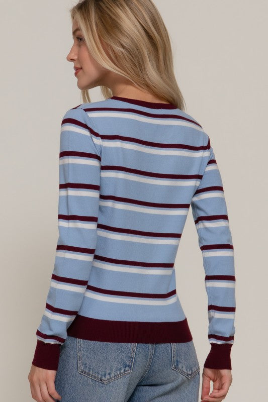 Woman wearing a blue and red striped sweater with a neutral background