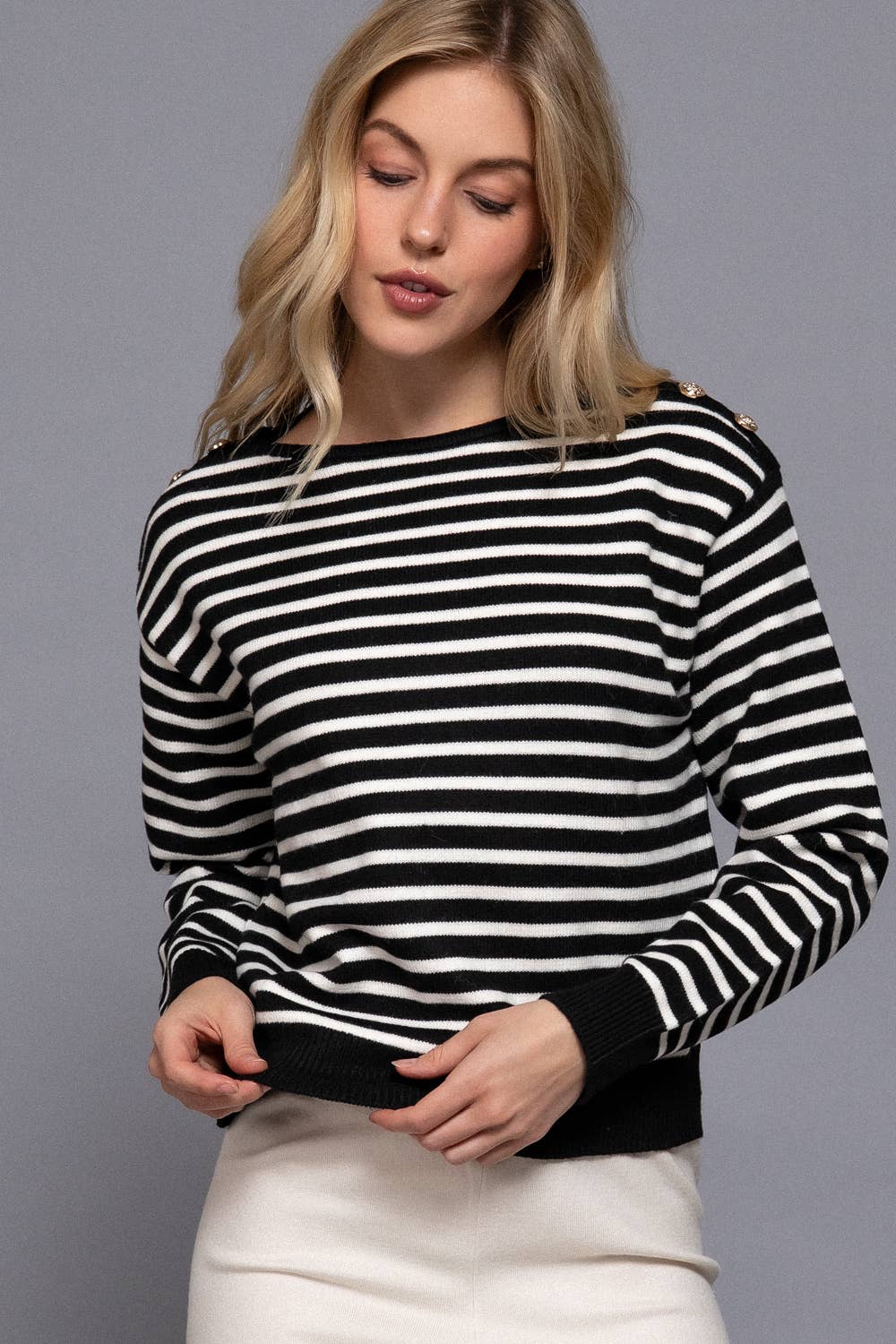 Woman wearing a black and white striped sweater against a gray background