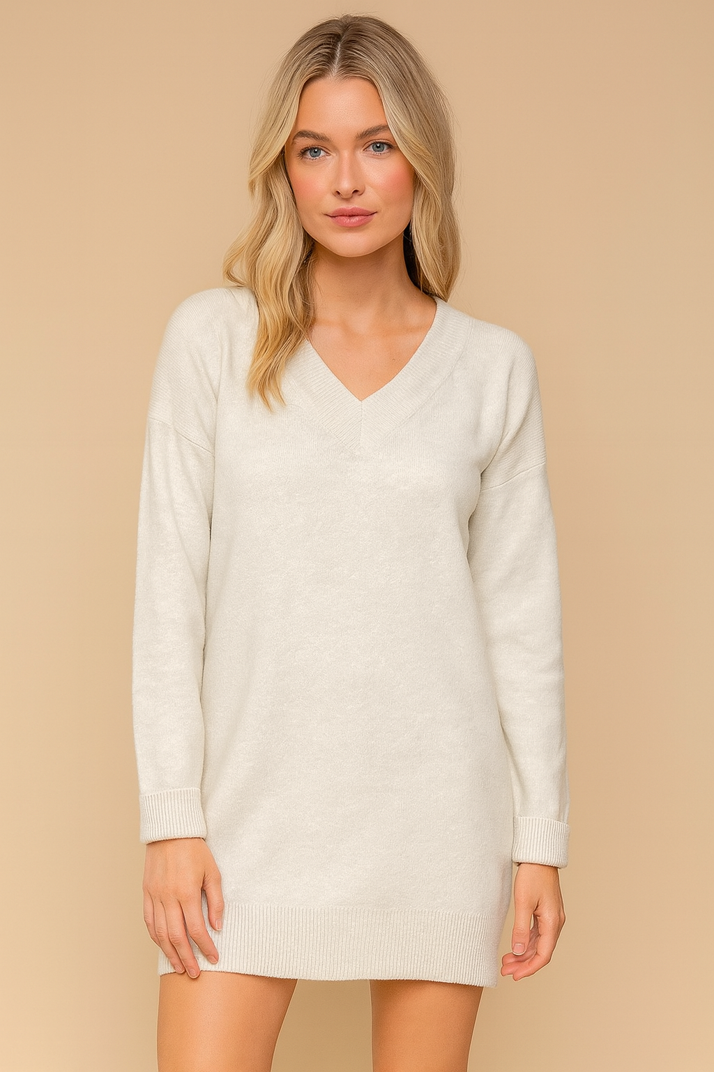 Woman wearing a gray sweater dress against a beige background