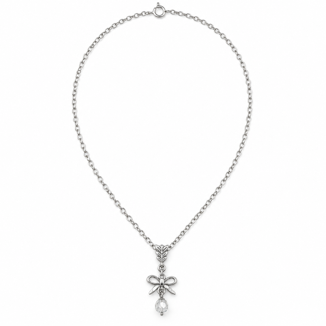 A silver-toned chain necklace featuring a bow-shaped pendant with a clear teardrop crystal hanging from the center, displayed against a solid white background.
