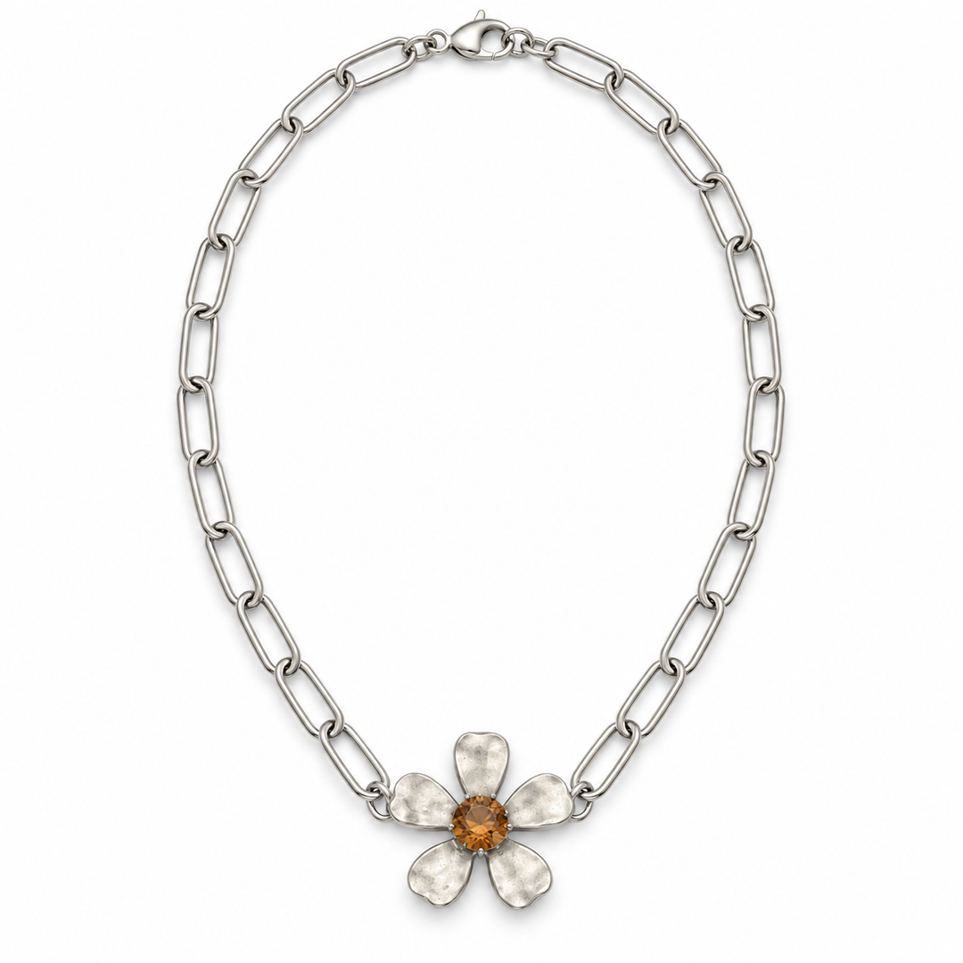 A silver-toned chain necklace featuring a textured five-petal flower pendant with a central amber-orange gemstone, displayed on a clean white background.