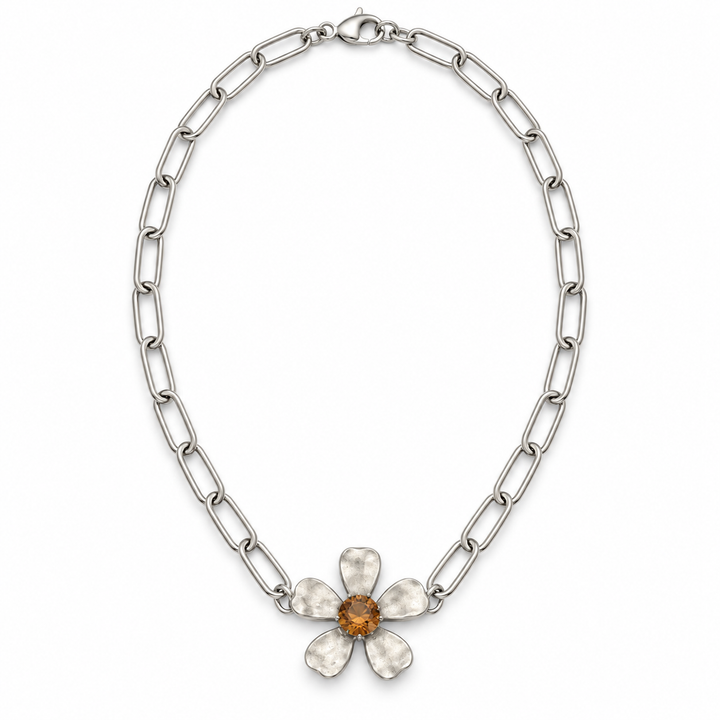 A silver-toned chain necklace featuring a textured five-petal flower pendant with a central amber-orange gemstone, displayed on a clean white background.