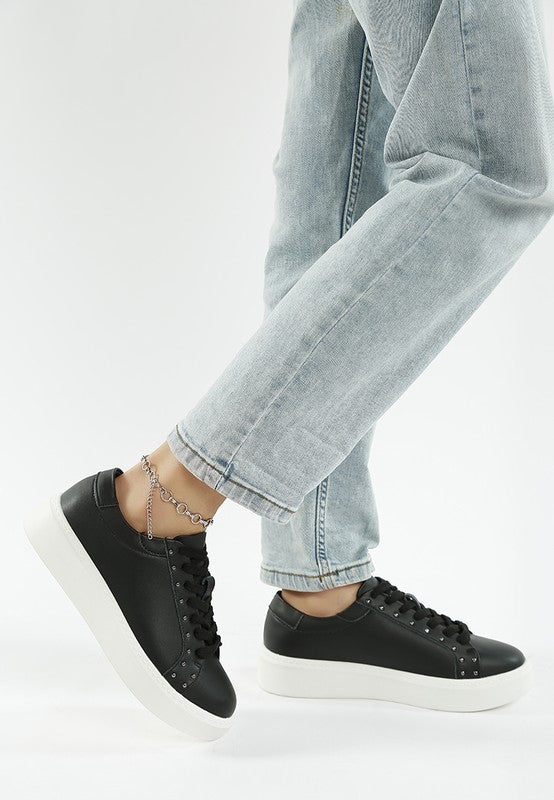 Black sneakers worn with light blue jeans on a white background