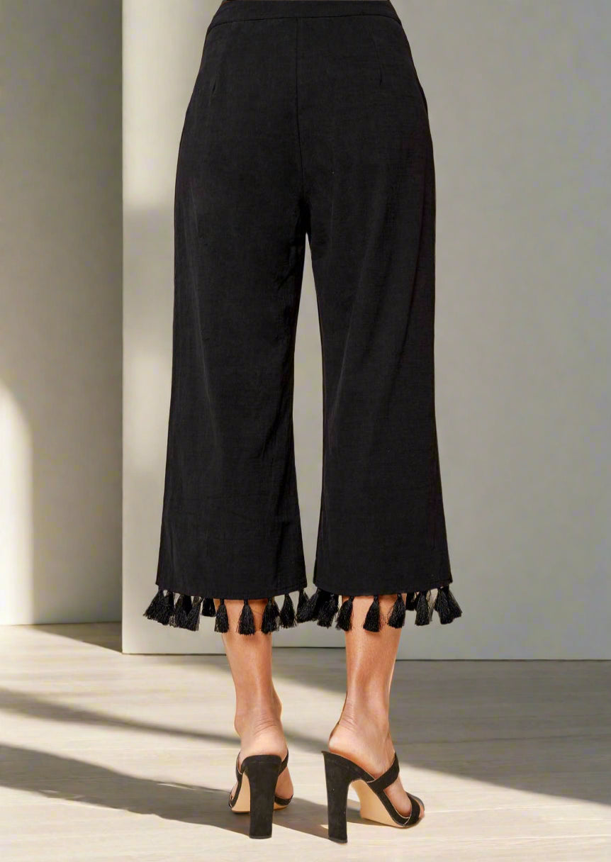 Black tasseled pants on a plain background