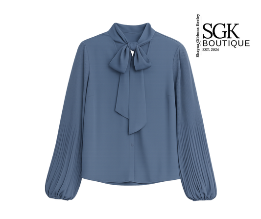 Blue blouse with a bow neckline on a white background, featuring the SGK Boutique logo.