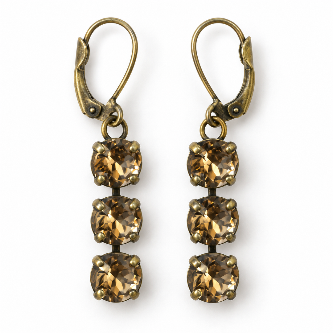 A pair of drop earrings with antique bronze leverback hooks and three faceted brownish-gold square crystals each, shown on a plain white background.