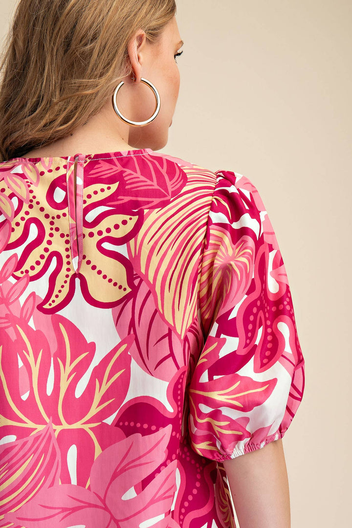 Woman wearing a pink and yellow floral dress with a beige background