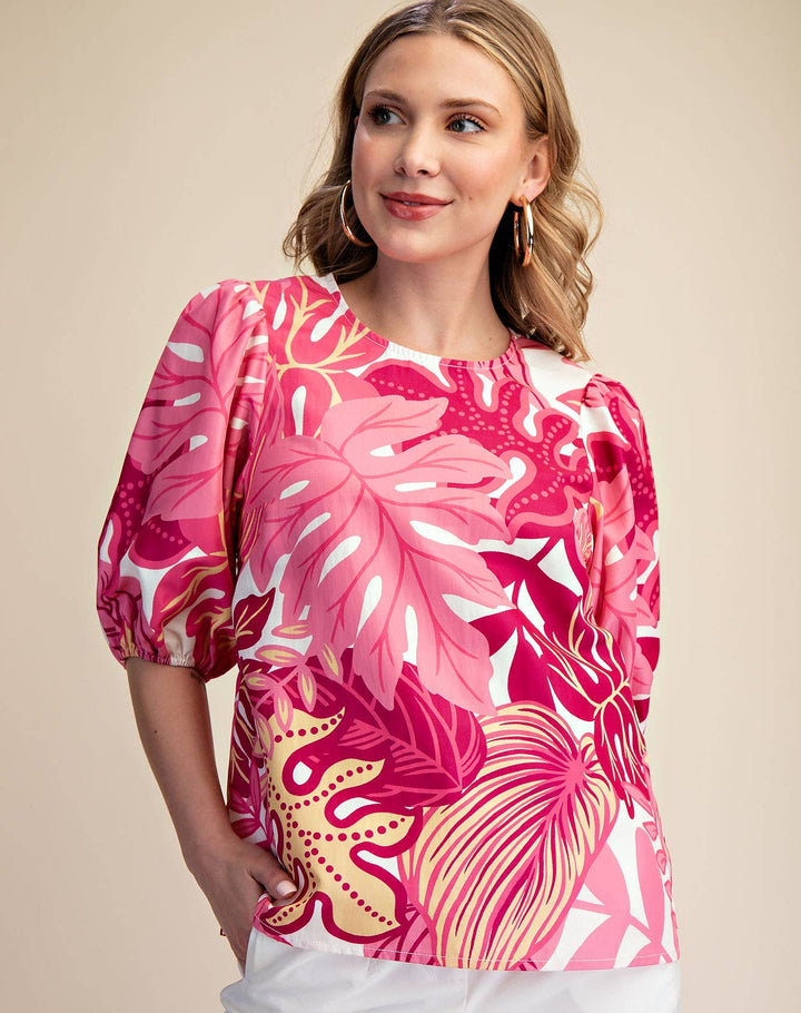 Woman wearing a pink floral blouse with white shorts on a beige background