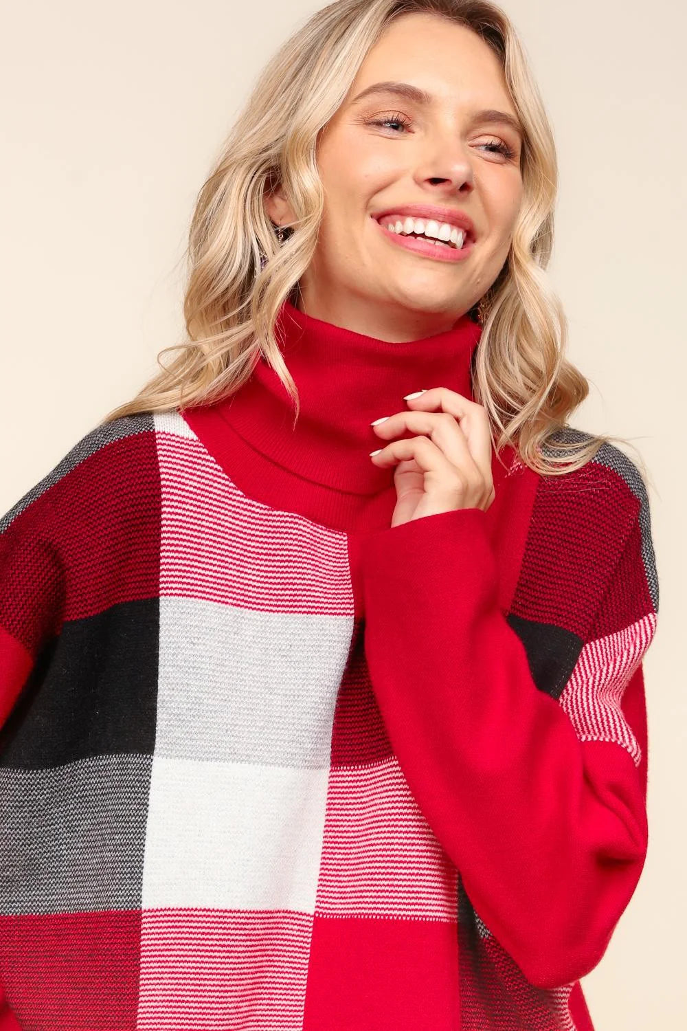 Woman wearing a red, black, and white checkered sweater on a beige background