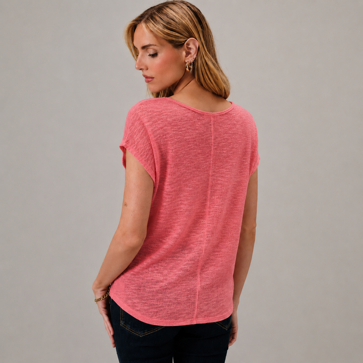 Woman wearing a pink t-shirt against a gray background