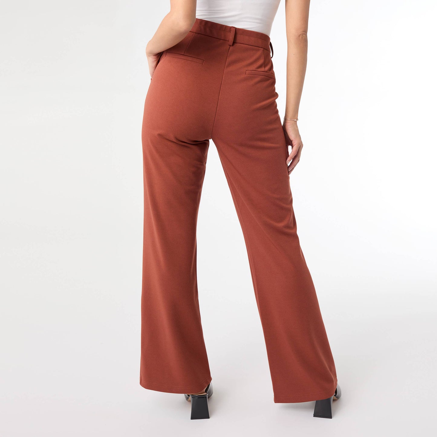 Terra cotta color pants worn by a person on a white background