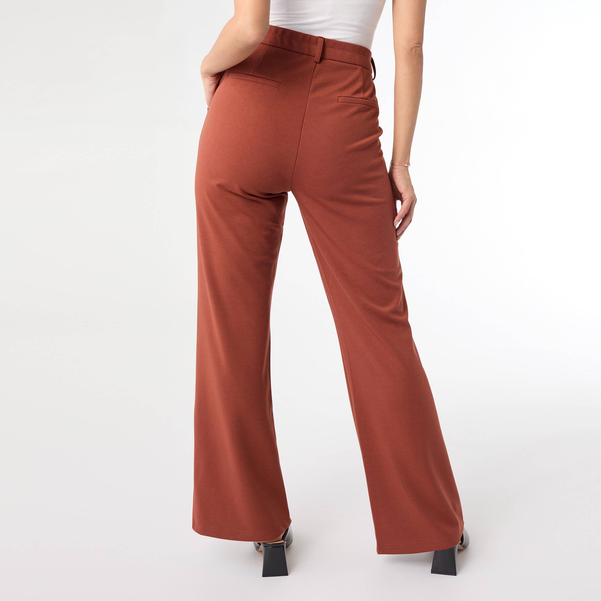 Terra cotta color pants worn by a person on a white background