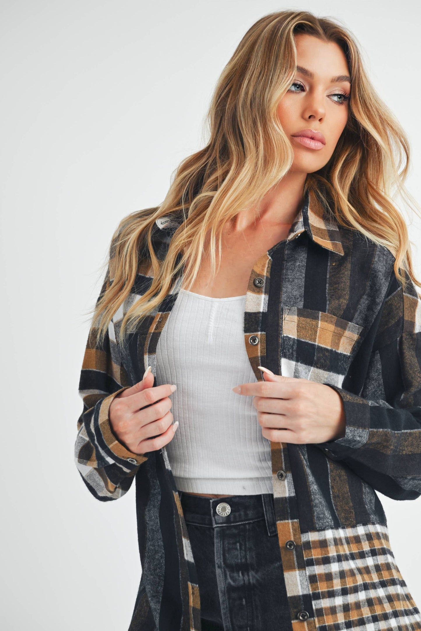 Woman wearing a plaid shirt over a white top on a plain background