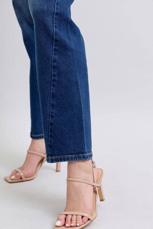 Close-up of blue jeans and beige high-heeled sandals on a plain background