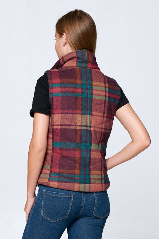 Person wearing a plaid vest over a black shirt and blue jeans on a white background