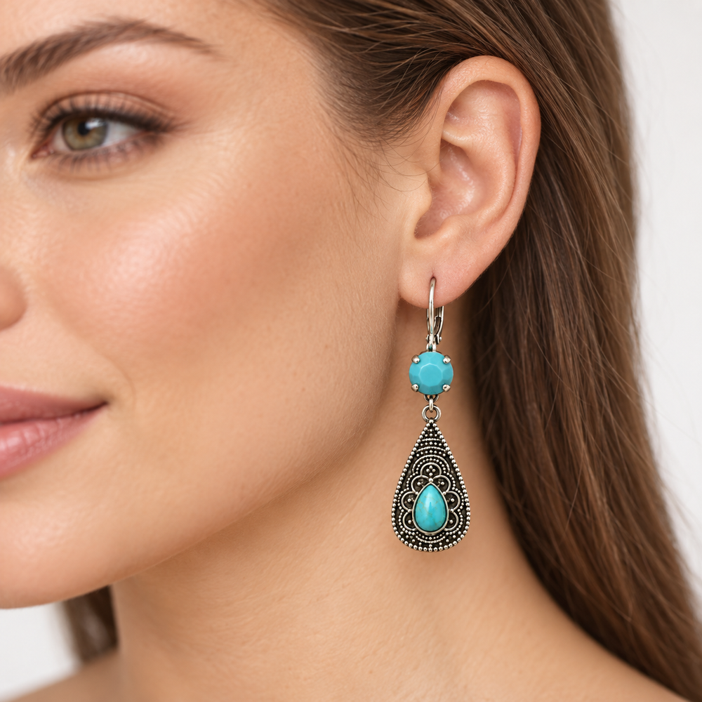 A close-up of a woman's ear wearing a dangling earring with a turquoise stone and ornate silver filigree details.