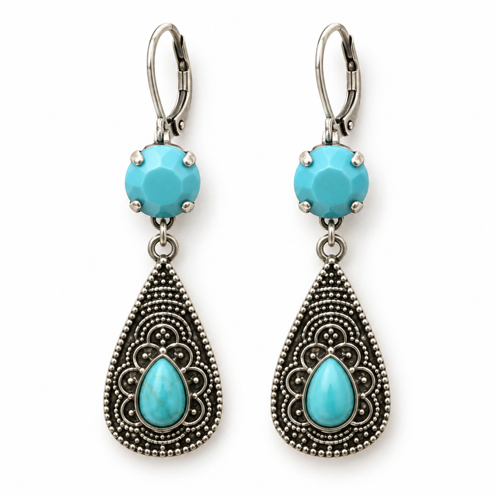 A pair of silver-toned dangle earrings featuring faceted turquoise blue beads at the top and ornate teardrop-shaped filigree drops with matching turquoise blue teardrop centers, shown on a plain white background.