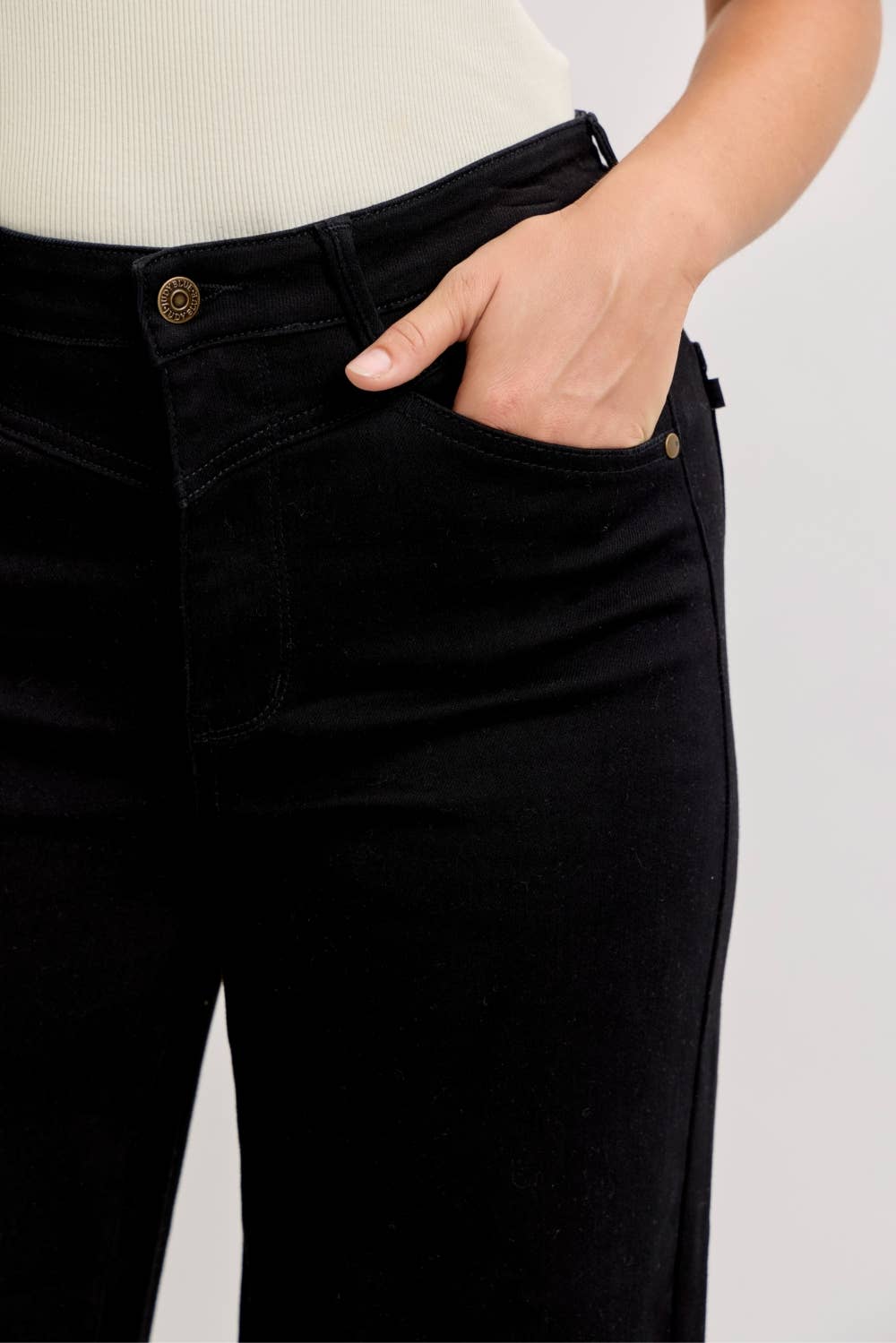 Person wearing black jeans with a plain background