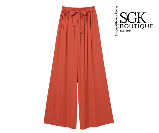 Rust wide-leg pants with a bow detail on a white background, featuring the SGK Boutique logo.