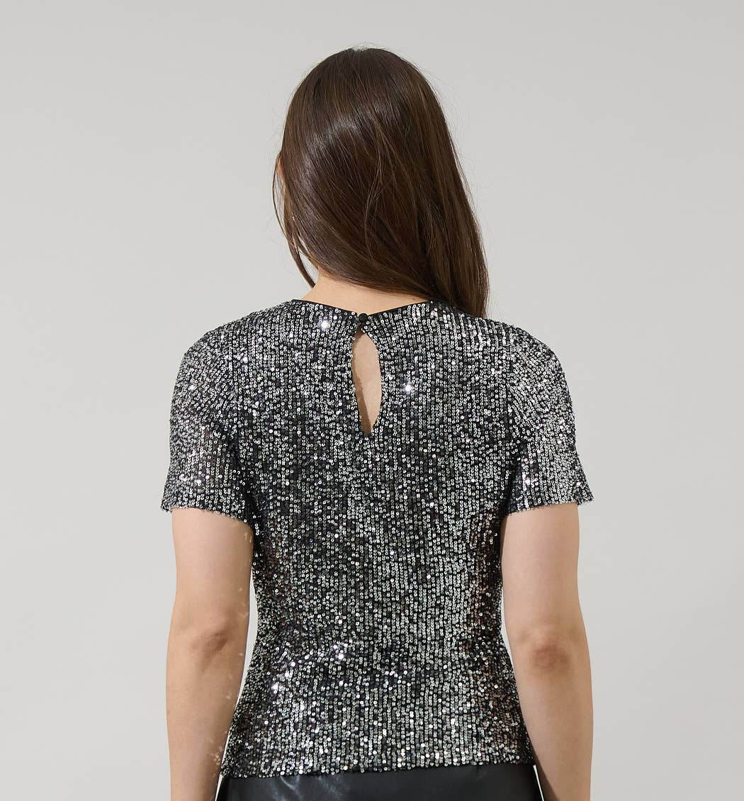 Woman wearing a sequin top and black leather skirt on a plain background