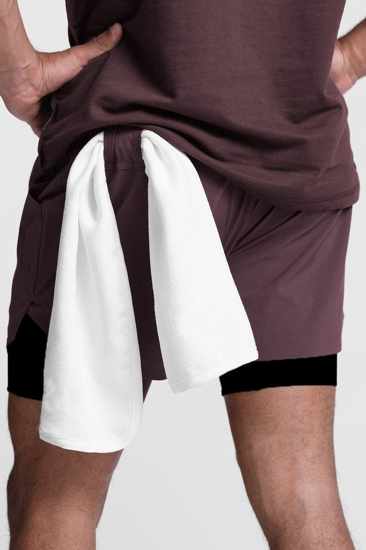 Person wearing a maroon shirt and white shorts with black accents on a plain background