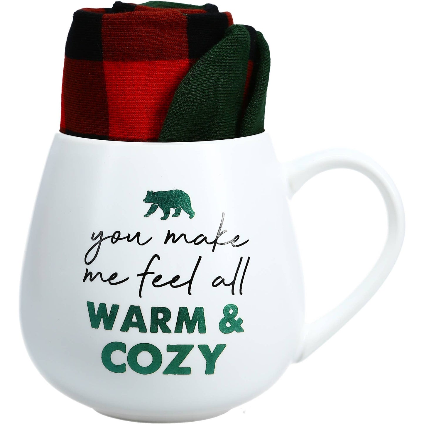 White mug with text 'you make me feel all warm & cozy' and a bear graphic, accompanied by a red and green checkered cloth.