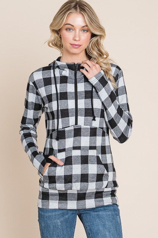 Woman wearing a black and white checkered hoodie against a beige background